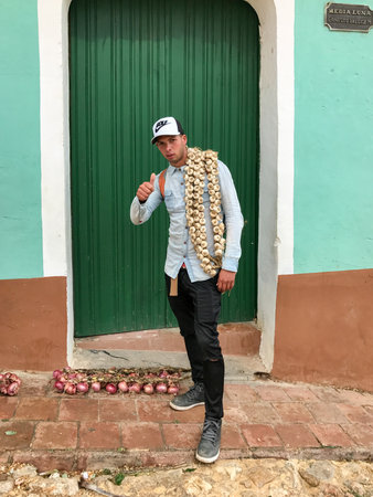 Trinidad, Cuba - January 12, 2017: Young man selling onions and garlic in the streets of Trinidad, Cuba.のeditorial素材