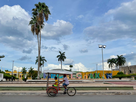 Hecelchakan, Mexico - May 26, 2021: Bicycle taxi by the colorful letters of the city of Hecelchakan in Campeche, Mexican.のeditorial素材