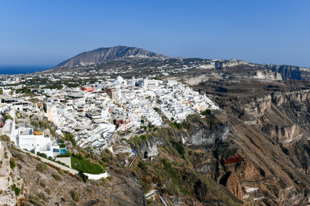 Charming view Fira village on Santorini island, Greece. Traditional famous blue dome church over the Caldera in Aegean sea. Traditional blue and white Cyclades architecture.の写真素材