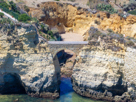 Aerial view of Algarve cliffs with Pinhao Fort Bridge as seen from the Atlantic Ocean in Lagos resort, Faro District, Portugal.の写真素材