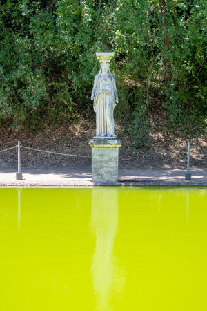 Villa Adriana, Tivoli: Ancient Roman statue in Canopus area, Villa Adriana, Tivoli. Limestone figure by green pool, surrounded by pine trees, showcasing classical Roman landscape design.の写真素材