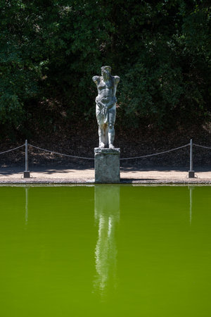 Villa Adriana, Tivoli: Ancient Roman statue in Canopus area, Villa Adriana, Tivoli. Limestone figure by green pool, surrounded by pine trees, showcasing classical Roman landscape design.の写真素材