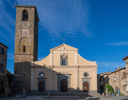 The Chiesa di San Donato in Civita di Bagnoregio, Italy, features a striking facade with a towering bell tower under a clear blue sky.の写真素材