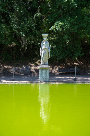 Villa Adriana, Tivoli: Ancient Roman statue in Canopus area, Villa Adriana, Tivoli. Limestone figure by green pool, surrounded by pine trees, showcasing classical Roman landscape design.の写真素材