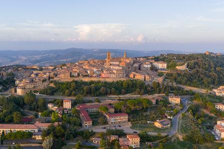 Aerial view of medieval Volterra hilltop center in Tuscany, showing stone buildings, defensive layout and surrounding rural landscape at sunset.の写真素材