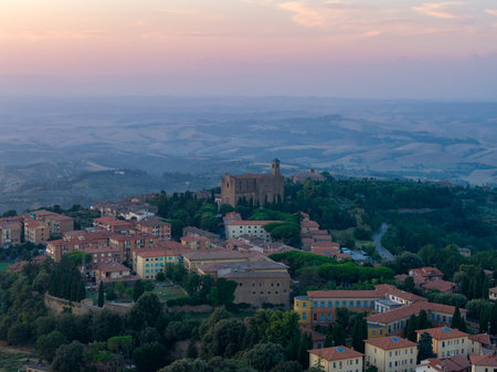 Aerial view of Chiesa dei Santi Giusto e Clemente and surrounding hillside houses near Volterra at sunset over the Tuscan countryside.の写真素材