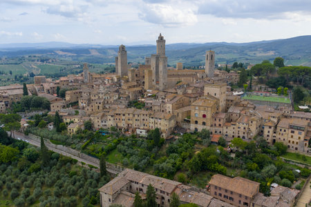Aerial view of San Gimignanoâs medieval stone towers and fortified walls rising above Tuscan hills in this former Via Francigena trading town.の写真素材