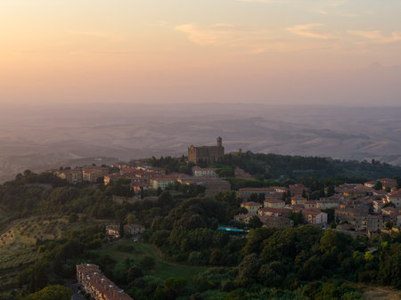 Distant view of Volterra hilltop and countryside at sunset, with Chiesa dei Santi Giusto e Clemente rising above medieval rooftops.の写真素材