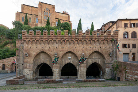 Fontebranda, a 13th-century Gothic fountain in Siena, Italy, features three arches and brick crenellations. Historically significant for its role in medieval water supply.の写真素材