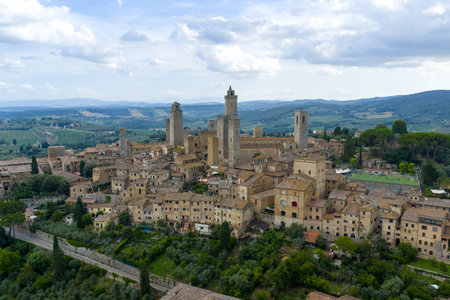 Aerial view of San Gimignanoâs medieval stone towers and fortified walls rising above Tuscan countryside, historic mercantile commune in Siena province.の写真素材