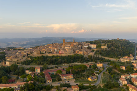 Aerial view of medieval Volterra, historic Etruscan hill town in Tuscany, with terracotta rooftops, fortress walls and surrounding countryside at dusk.の写真素材