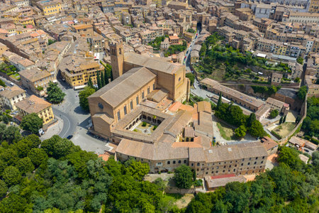 Gothic Basilica Cateriniana San Domenico in Siena, Italy, known for its brick facade and 13th-century origins. Overlooks winding medieval streets under bright daylight.の写真素材