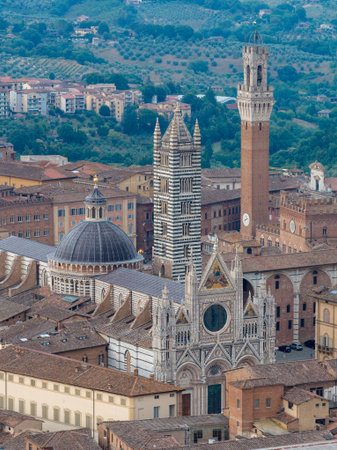 Siena Cathedral, an architectural masterpiece in black and white marble, features Gothic towers and a richly detailed facade. Located in Siena, Italy, it exemplifies Italian Gothic design.の写真素材