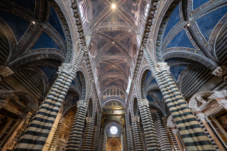 Siena, Italy - Jul 19, 2025: Interior of Siena Cathedral, Italy, showcasing Gothic architecture with black-white marble stripes, vibrant frescoes, and starry vaults.の写真素材