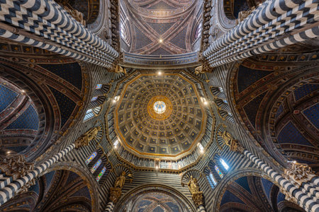 Siena, Italy - Jul 19, 2025: Siena Cathedral's striped marble columns and coffered dome create a dramatic Gothic interior. Natural light enhances the intricate black and white patternsの写真素材