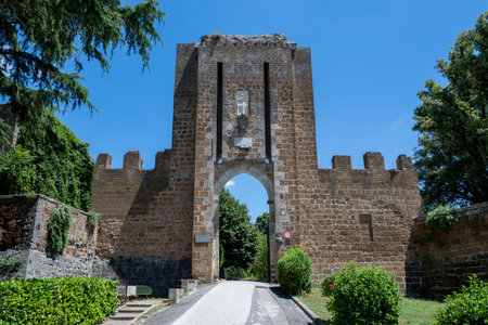 Medieval Albornoz Fortress in Orvieto, Italy, features robust stone walls and crenellations. Built in the 14th century, it commands strategic views, now surrounded by lush greenery under a clear sky.の写真素材