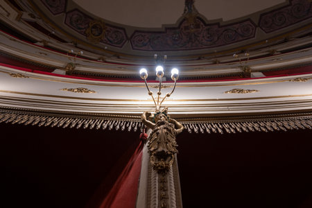 Volterra, Italy - Jul 21, 2025: Ornate caryatid lamp and gilded stucco decoration inside 19thâcentury Teatro Persio Flacco in Volterra, historic Tuscan hill town.の写真素材