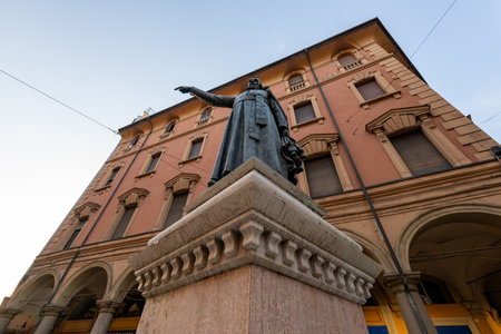 Bologna, Italy - Jul 23, 2025: Low-angle view of the bronze Monumento a Ugo Bassi against porticoed...