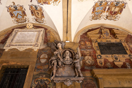 Bologna, Italy - Jul 23, 2025: Stucco memorial, frescoed coats of arms and Latin epigraphs in the...