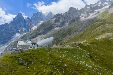 Aerial view of an alpine refuge above Pavillon near Courmayeur, with steep grassy slopes and rocky Mont Blanc peaks in summer.の写真素材