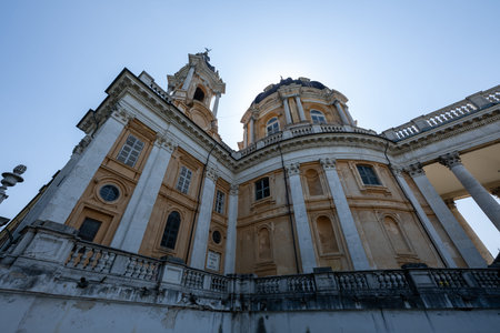 Low-angle view of the 18th-century Baroque Basilica of Superga near Turin, showing its dome, bell tower and stuccoed colonnade against blue sky.の写真素材