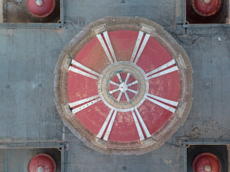 Overhead view of the Corpus Christi Parish Church dome in Ghasri, showing a red-and-white segmented roof with central star motif against grey stonework.の写真素材