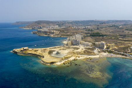Aerial view of Xwejni Bay near Zebbug, Malta, showing rocky shoreline, clear turquoise water, small coves, and coastal buildings on the headland.の写真素材