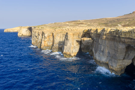 Limestone sea cliffs on Gozo near Gharb, Malta, with deep-blue Mediterranean water and rugged...