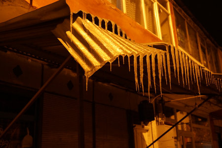 Icicles hanging from the roof of a building at night.