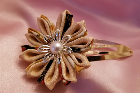Light brown Japanese kanzashi hand made hair clip constructed from kimono material on a pink fabric backgroundの写真素材