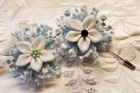 Cream and light blue colored Japanese kanzashi hand made bridal set constructed from kimono material on a creamy fabric background. The set consists of a hair clip for the bride, and a lapel pin for the groom.の写真素材