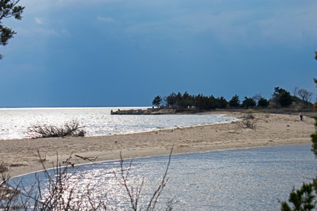 An approaching springtime storm darkens the sky at Sandy Hook Bay as the setting sun's rays reflect on the water -19の写真素材