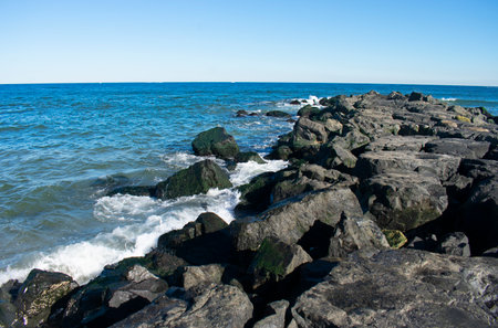 Surf crashes into shore and rock jetty on a sunny autumn day in Asbury Park, New Jersey -03の写真素材