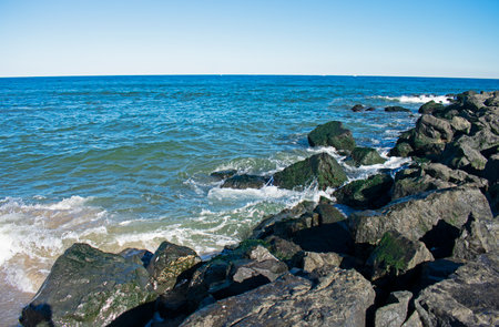 Surf crashes into shore and rock jetty on a sunny autumn day in Asbury Park, New Jersey -04の写真素材