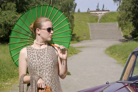 Beautiful girl with a green umbrella in a summer gardenの写真素材