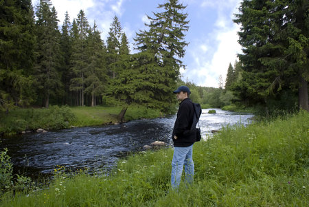 Man on coast of the wood river looks at the opposite sideの写真素材