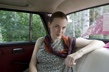 Beautiful young girl on back sitting of the carの写真素材