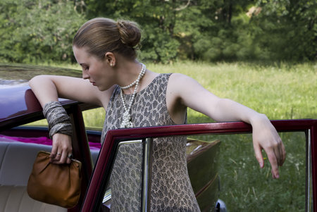 Beautiful girl at the car on a green wood backgroundの写真素材