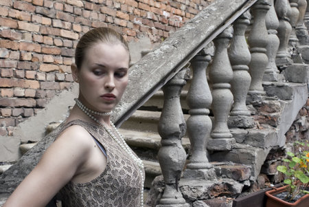 Beautiful girl on a old ladder and a brick wall backgroundsの写真素材