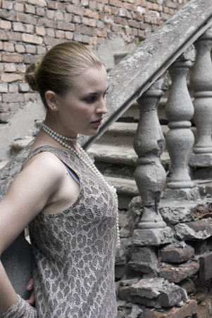 Beautiful girl on a background of an old ladder and a brick wallの写真素材