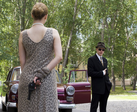 Beautiful stylish girl with a revolver before the car driverの写真素材