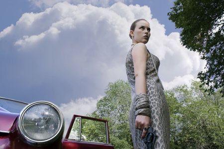 Beautiful stylish girl with a revolver in a hand at the carの写真素材