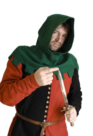Medieval robber in an ancient red and black suit checks an edge of a knifeの写真素材