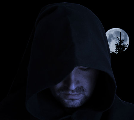 Man in an ancient hood on a full moon backgroundの写真素材