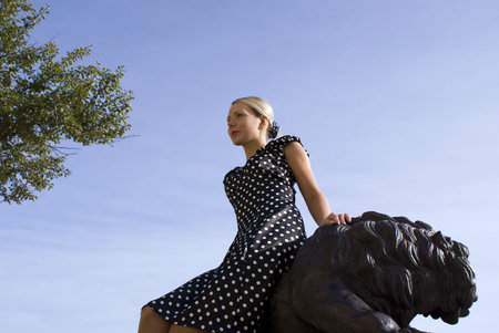 Beautiful smiling girl beside with a statue of a lionの写真素材
