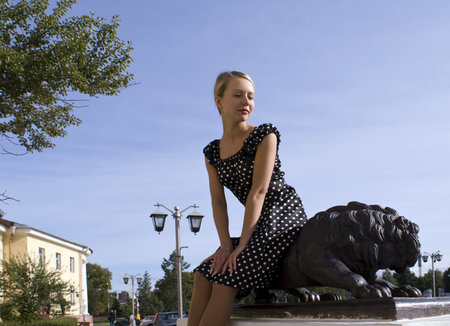 Beautiful smiling girl beside with a statue of a lionの写真素材