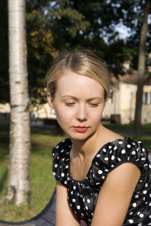 Beautiful stylish girl on a bench in a summer gardenの写真素材