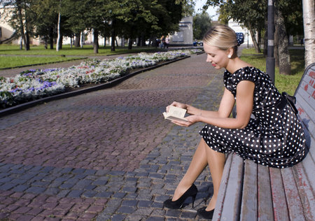 Beautiful stylish girl on a bench in a summer gardenの写真素材