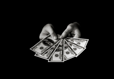 Hands with packs of dollars over black
