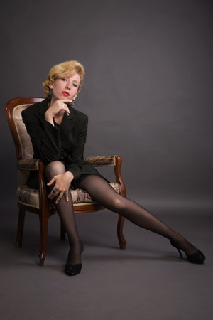 Beautiful young woman in a in a  business suit sits in an armchairの写真素材